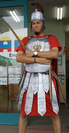 a man dressed as a roman soldier with his arms crossed, standing in front of a store