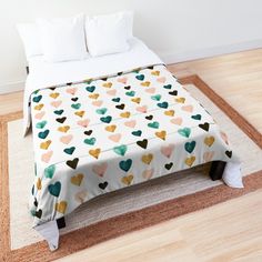 a bed with hearts printed on it in a white room next to a wooden floor