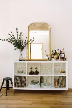 a white shelf filled with lots of books and other items on top of a hard wood floor