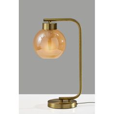 a table lamp with a glass ball on the base and a gold metal arm, against a gray background