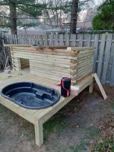 a hot tub built into the side of a wooden deck in a yard with a fence behind it