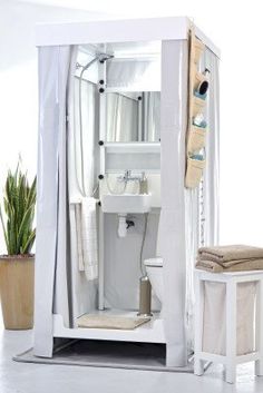 a white toilet sitting next to a sink in a bathroom under a shower curtain with an open door