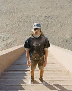 a man standing at the top of a flight of stairs with his skateboard in hand