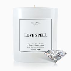 a candle that is next to a diamond on a white surface with the words love spell written across it