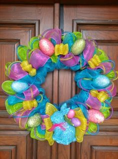 a colorful wreath is hanging on the front door with easter eggs and bows around it