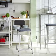 two stools sitting in front of a counter with plates and bowls on top of it