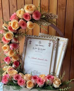 an ornate frame with flowers on it and a certificate in front of the frame is surrounded by greenery