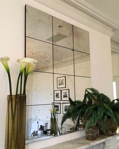 there is a mirror and some flowers in the vases on the fireplace mantel