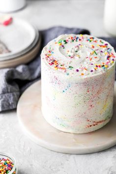 a white cake with sprinkles sitting on top of a plate