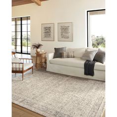 a living room filled with furniture and a white couch next to a large window on top of a hard wood floor