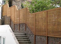 a wooden fence next to a brick wall with steps and railings on each side