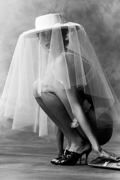 black and white photograph of a woman kneeling down with her veil over her head, wearing high heels