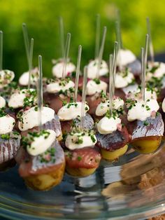 small appetizers are arranged on a glass platter with toothpicks and garnishes