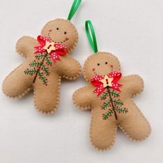 two felt gingerbread man ornament hanging from green ribbon