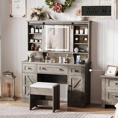 an old dresser with a mirror, stool and flowers on the top shelf in front of it