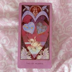 a card with two hearts on it sitting on a pink bed sheet in the shape of a heart