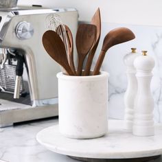 kitchen utensils in white ceramic container on marble counter