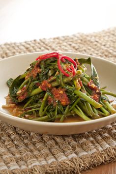 a white plate topped with green beans covered in sauce