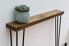 a potted plant sitting on top of a wooden shelf next to a white wall