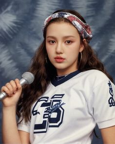 a young woman holding a microphone and wearing a white shirt with blue letters on it