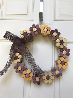 a wreath made out of wine corks is hanging on the front door with a ribbon