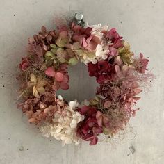 a wreath is hanging on the wall with dried flowers and foliages around it,