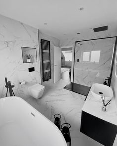 a white bathroom with black accents and marble walls, along with a freestanding bathtub