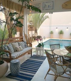 an instagram photo of a living room with furniture and plants on the floor next to a swimming pool