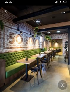 an empty restaurant with green booths and brick walls