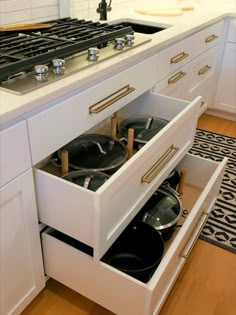 two pots and pans are sitting in the drawer on the stove top, which is open