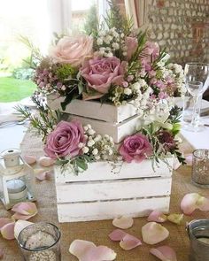 a wooden box filled with flowers on top of a table next to other glassware