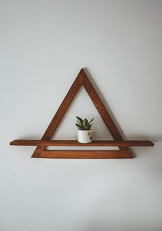 a triangle shelf with a potted plant in it on top of a white wall