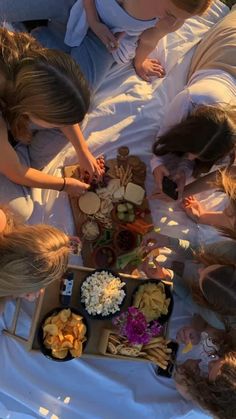 several people are gathered around a table with food on it