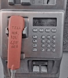 an old fashioned pay phone with writing on the front and back panel that says tell her you love her