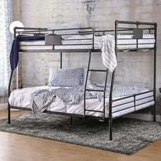 a metal bunk bed sitting on top of a wooden floor next to a brick wall