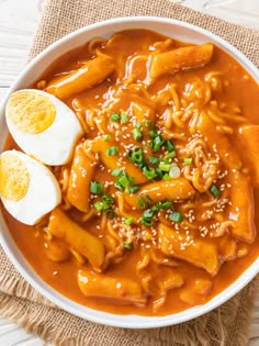 a white bowl filled with noodles and hard boiled eggs