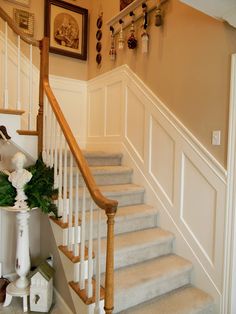 there is a white staircase with flowers on the bannister and pictures above it