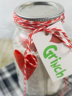 a glass jar filled with white sand and red twine on top of a checkered table cloth