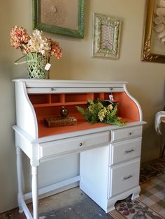 a white desk with an orange top and flowers on it in front of a wall