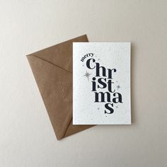 a card with the words merry christmas and stars on it, sitting next to an envelope