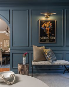 a living room with blue walls and artwork on the wall, along with a white coffee table