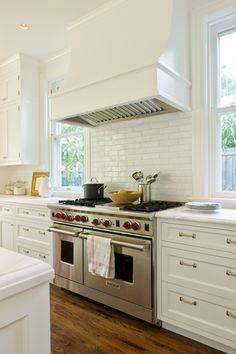 a stove top oven sitting inside of a kitchen next to white cabinets and counter tops