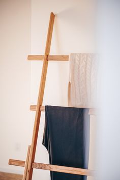 a ladder leaning up against a white wall next to a black bag and a blanket