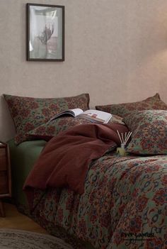 a bedroom with a bed covered in red and green comforter next to a night stand