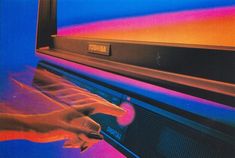 a hand is pressing the button on an old television screen that's turned blue and pink