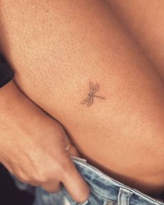 a small dragonfly tattoo on the back of a woman's stomach