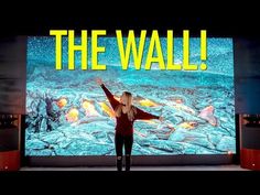 a woman standing in front of a large screen with the words the wall on it