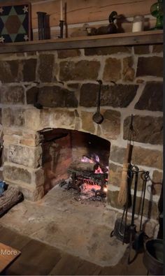 an old stone fireplace in a rustic living room with wood burning and pots on the mantle