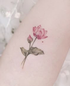 a small pink flower on the back of a woman's thigh, with green leaves