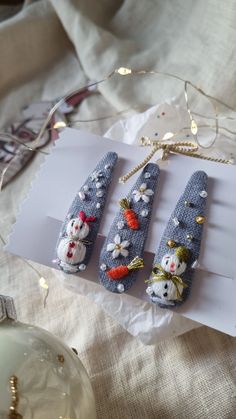 three snowmen are sitting on top of a piece of paper next to some ornaments